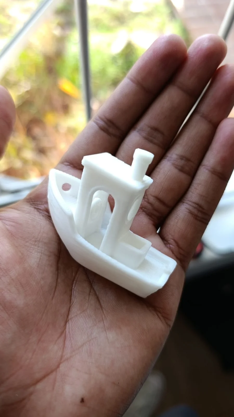 Shay's first ever 3D print — a 3DBenchy test boat — held in hand