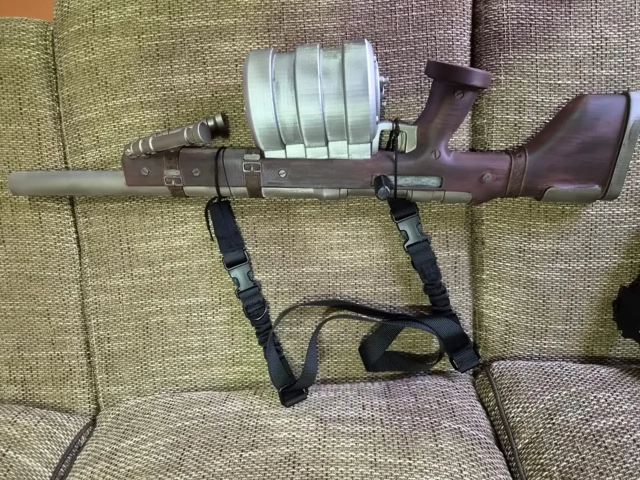 Seras's Harkonnen cannon laid on its side, showing the five-disc drum magazine, weathered wood-effect stock and painted leather straps
