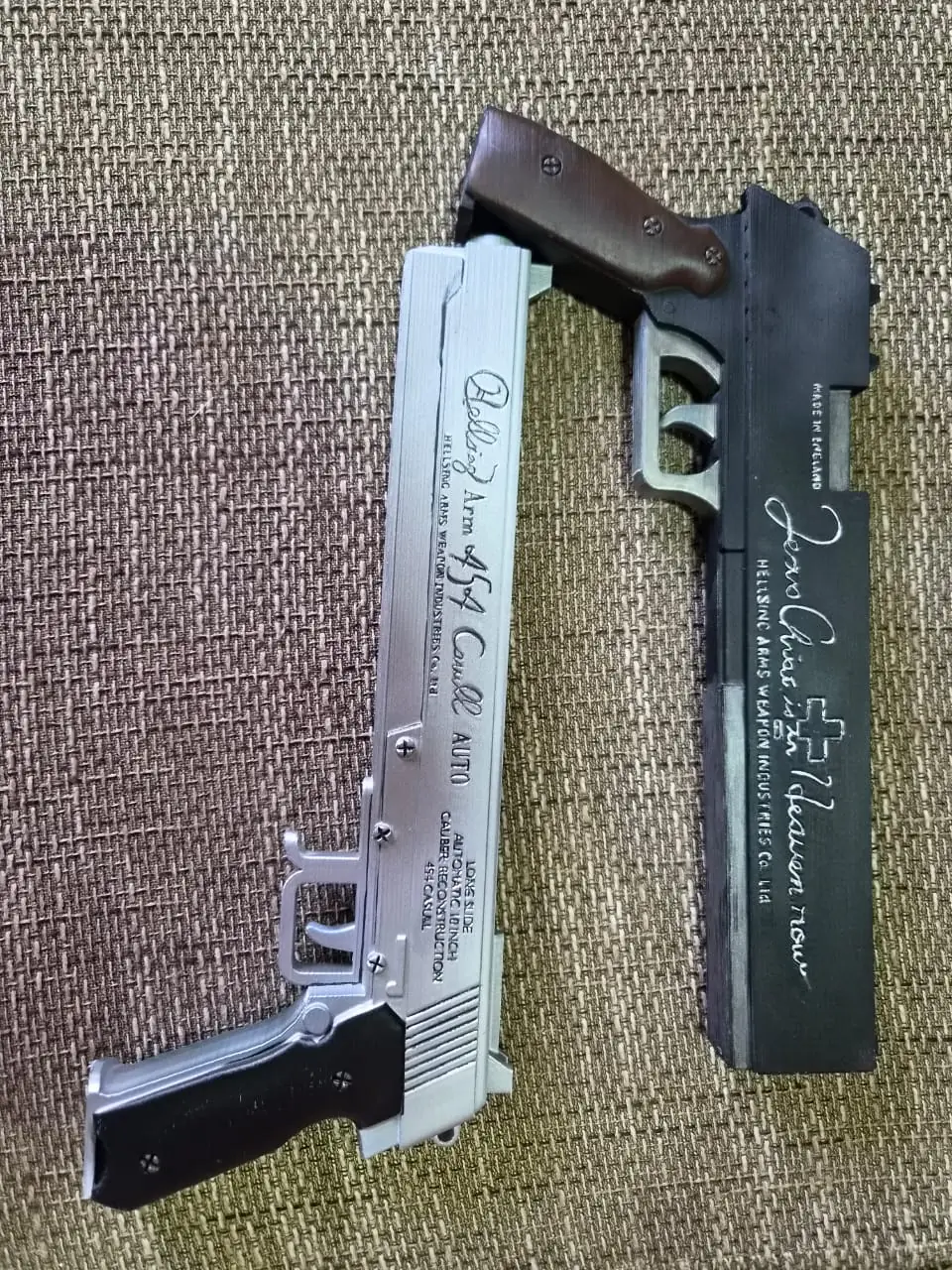 The Casull and Jackal laid flat, with the Jackal's cross emblem and 'Jesus Christ is in Heaven now' script picked out in silver