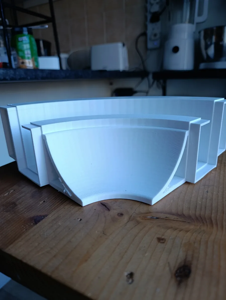 A white PETG 3D printed corner piece straight off the printer, showing the swept LED channel and flat registers on each end that locate it inside the aluminium extrusion