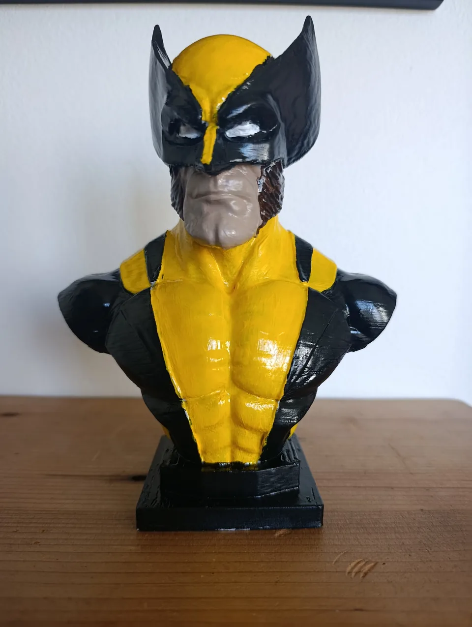 3D printed Wolverine bust from the front, in the classic yellow and black suit with the finned cowl, on a stepped black base